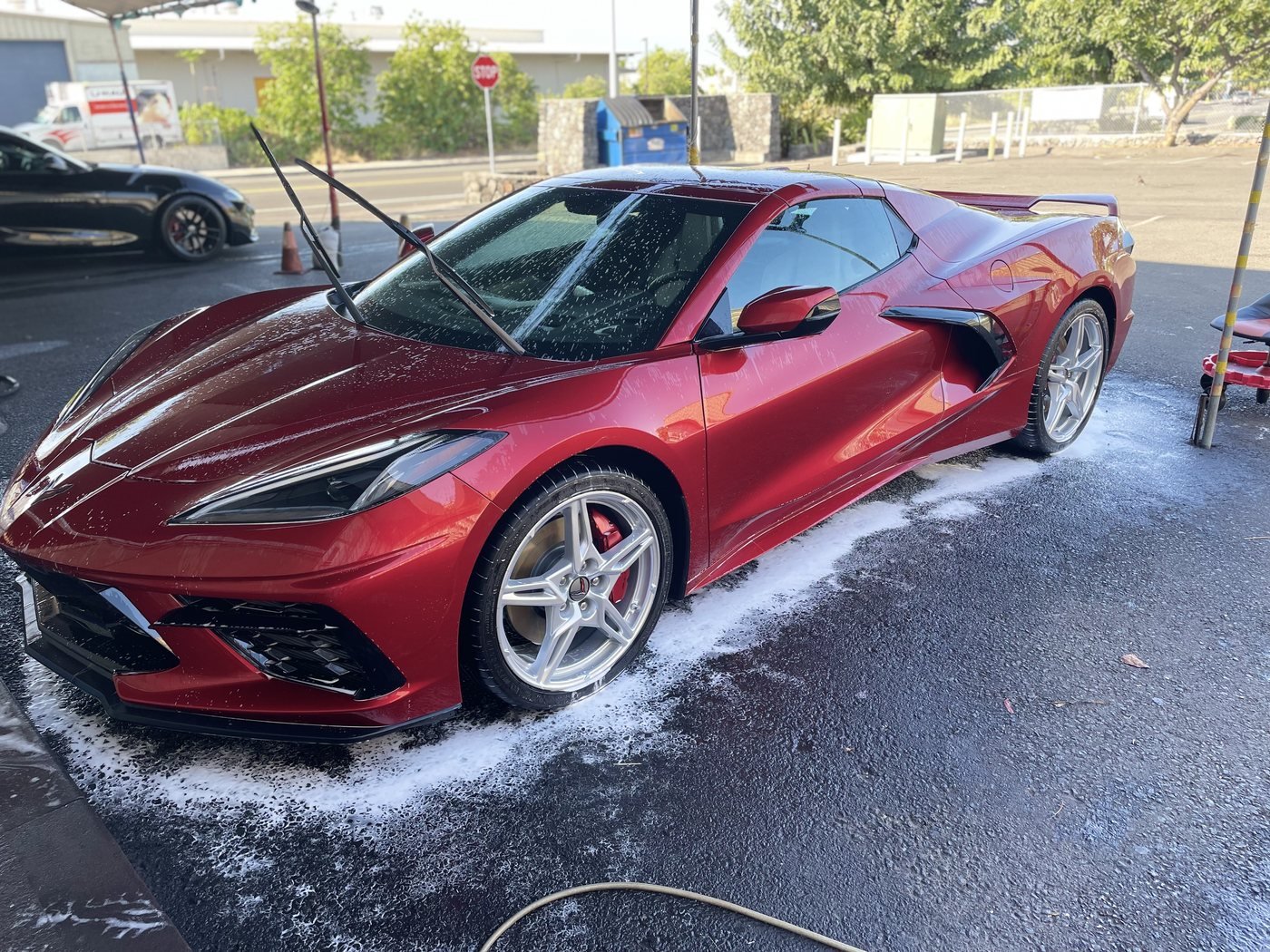 Candy-red Corvette covered in wash foam under the SilvaShine wash tent in Kona